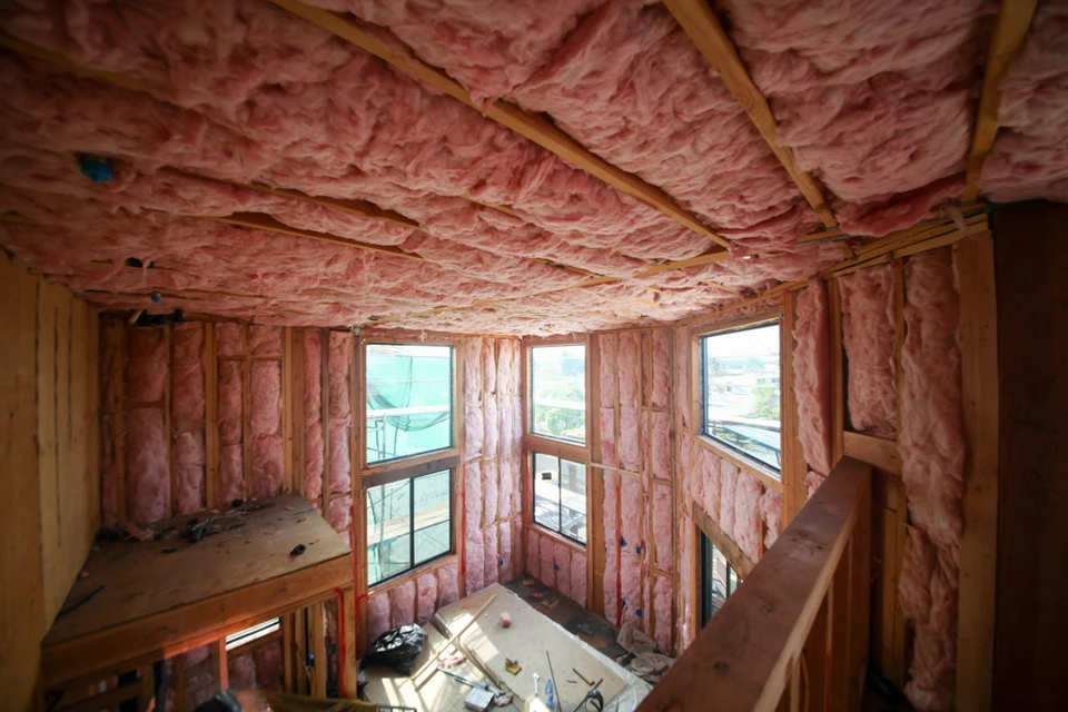 Chantier de construction r&eacute;sidentielle en cours, structure bois avec isolation thermique rose entre montants et solives apparentes