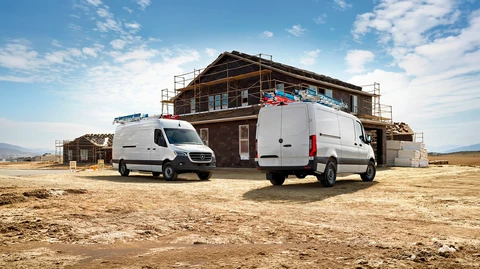 Deux fourgons utilitaires blancs Mercedes-Benz Sprinter stationnés sur un chantier de construction