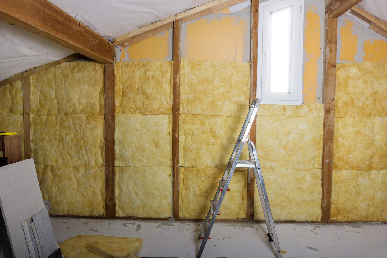 Chantier de rénovation intérieure dans combles aménageables avec ouvrier installant isolation thermique