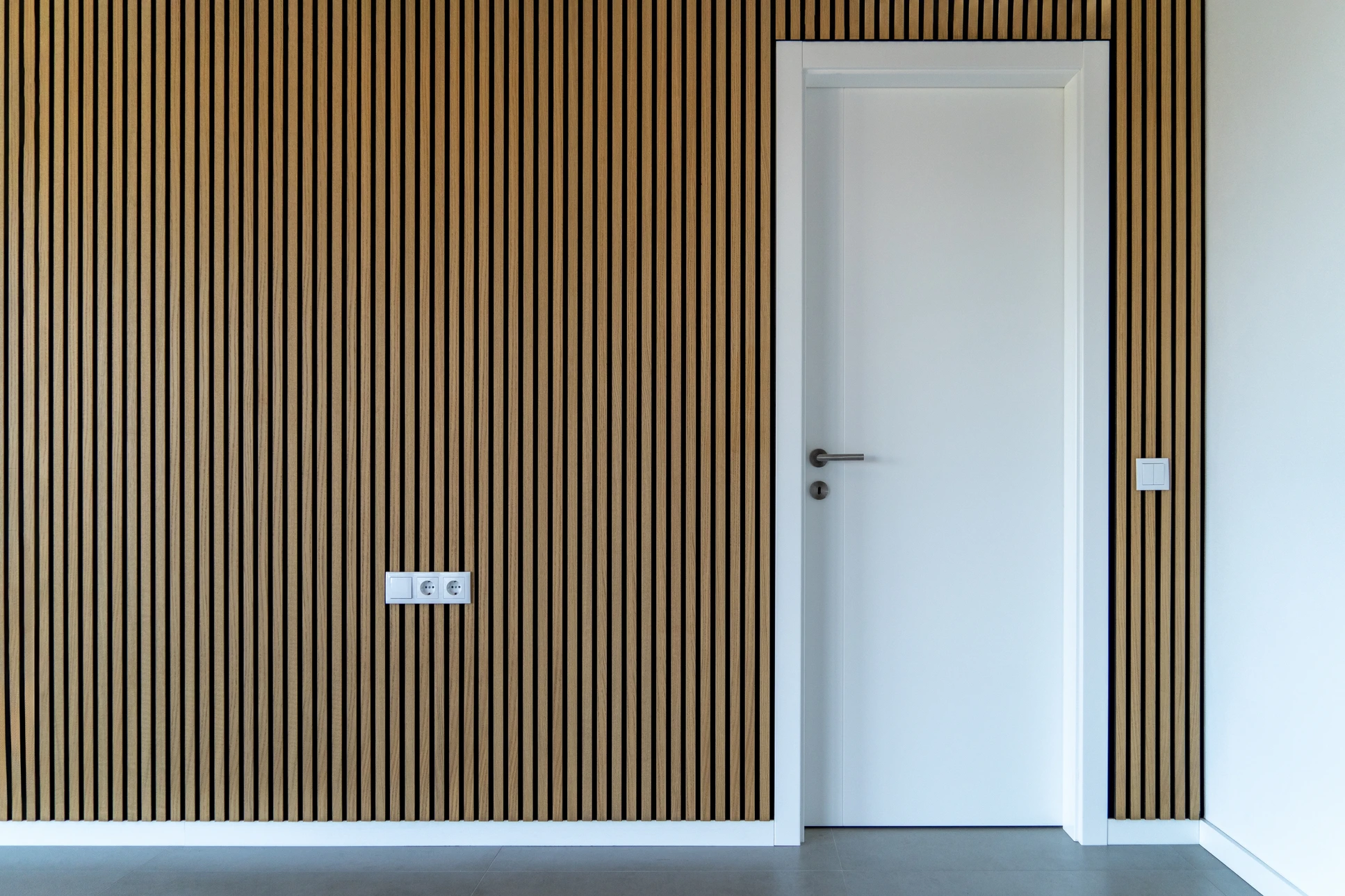 Intérieur de bâtiment en construction, ouvrier en combinaison de protection blanche et gants installant de la laine de verre jaune entre montants métalliques d'une cloison