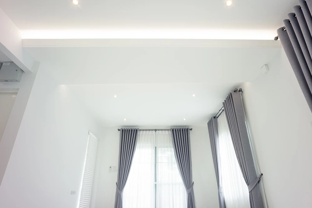 Chantier de construction intérieur avec ouvriers installant un plafond suspendu
