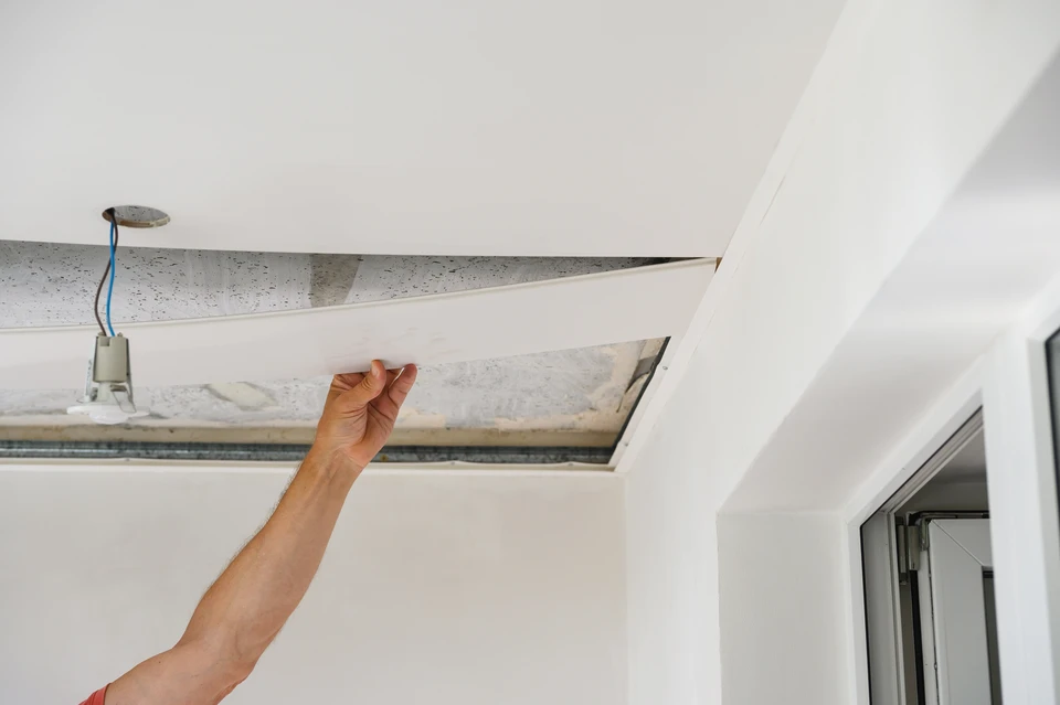 Ouvrier professionnel effectuant des travaux de finition au plafond dans un intérieur moderne