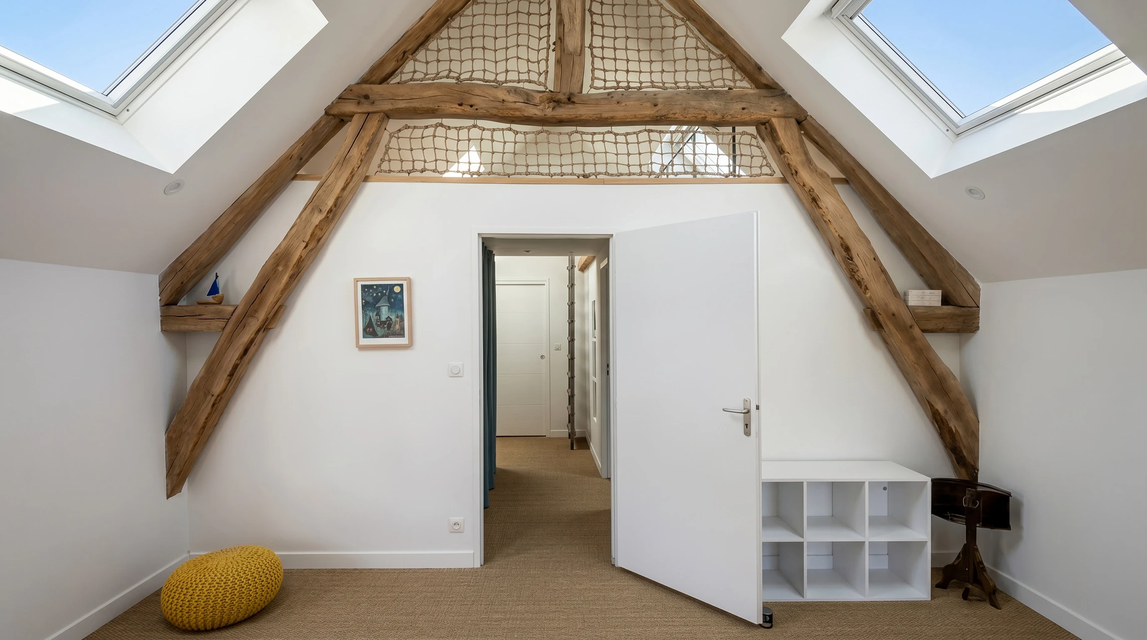 Intérieur de bâtiment en construction, ouvrier en combinaison de protection blanche et gants installant de la laine de verre jaune entre montants métalliques d'une cloison